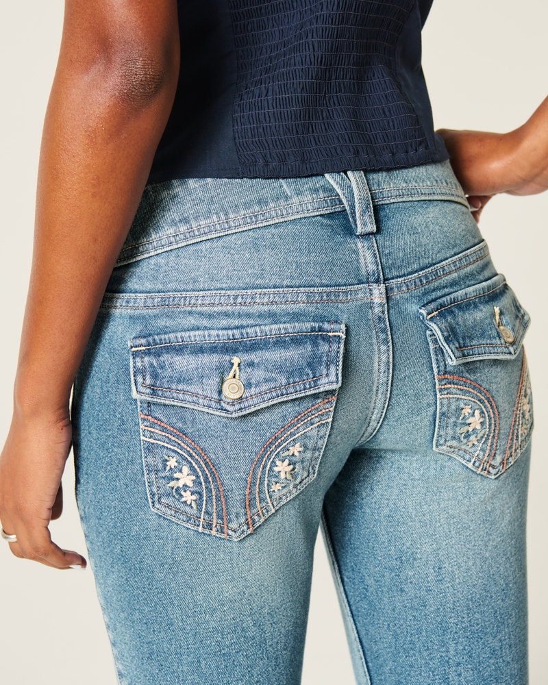 hüftig geschnittene mittelblaue bootcut-jeans mit blumenstickerei.