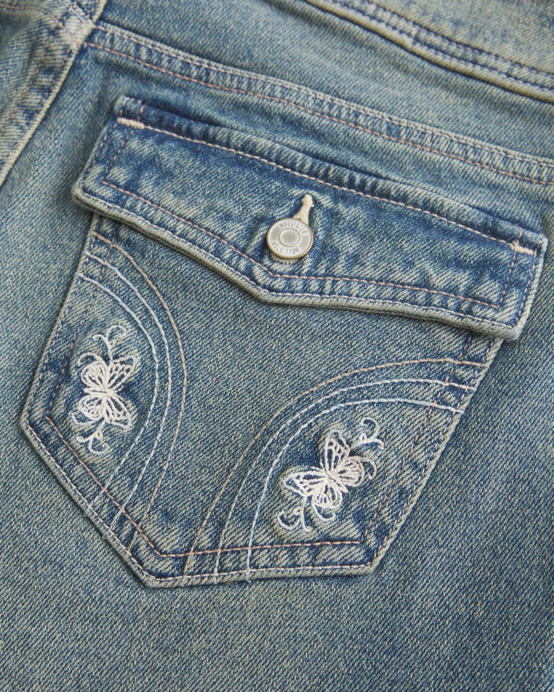 hüftig geschnittene mittelblaue bootcut-jeans mit blumenstickerei.